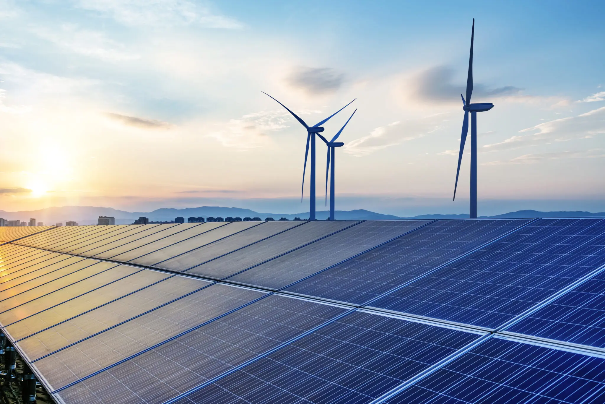 Solar panels and wind turbines at sunset.