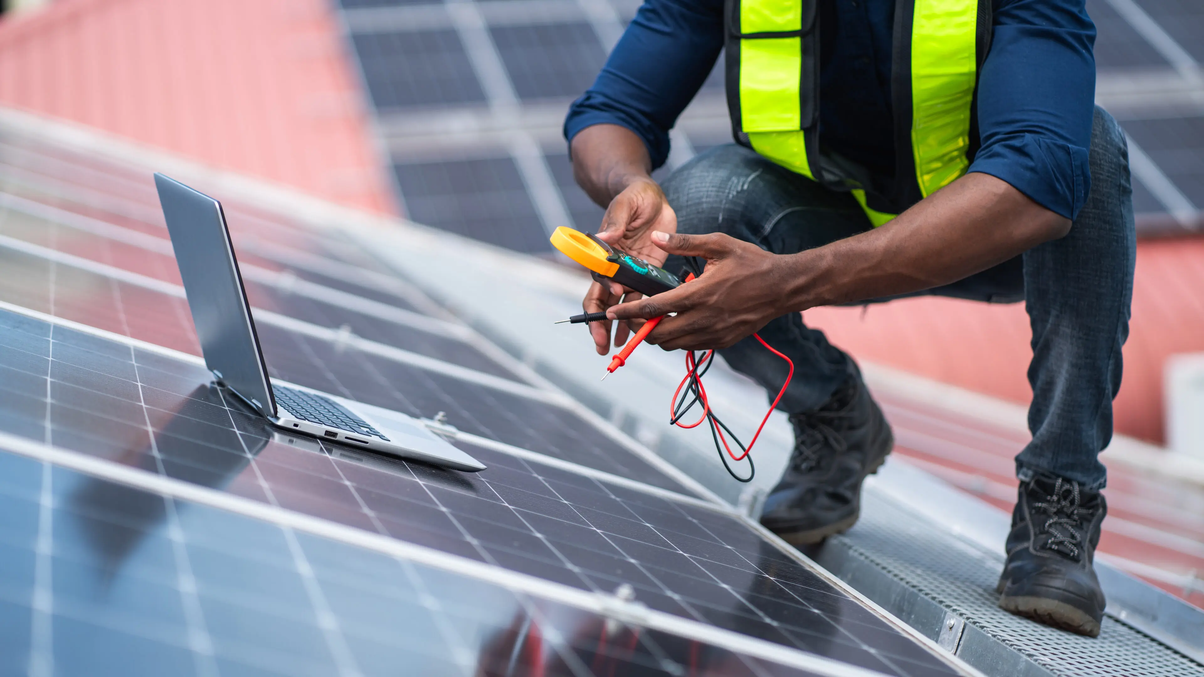 Technician measuring solar panel efficiency with laptop.