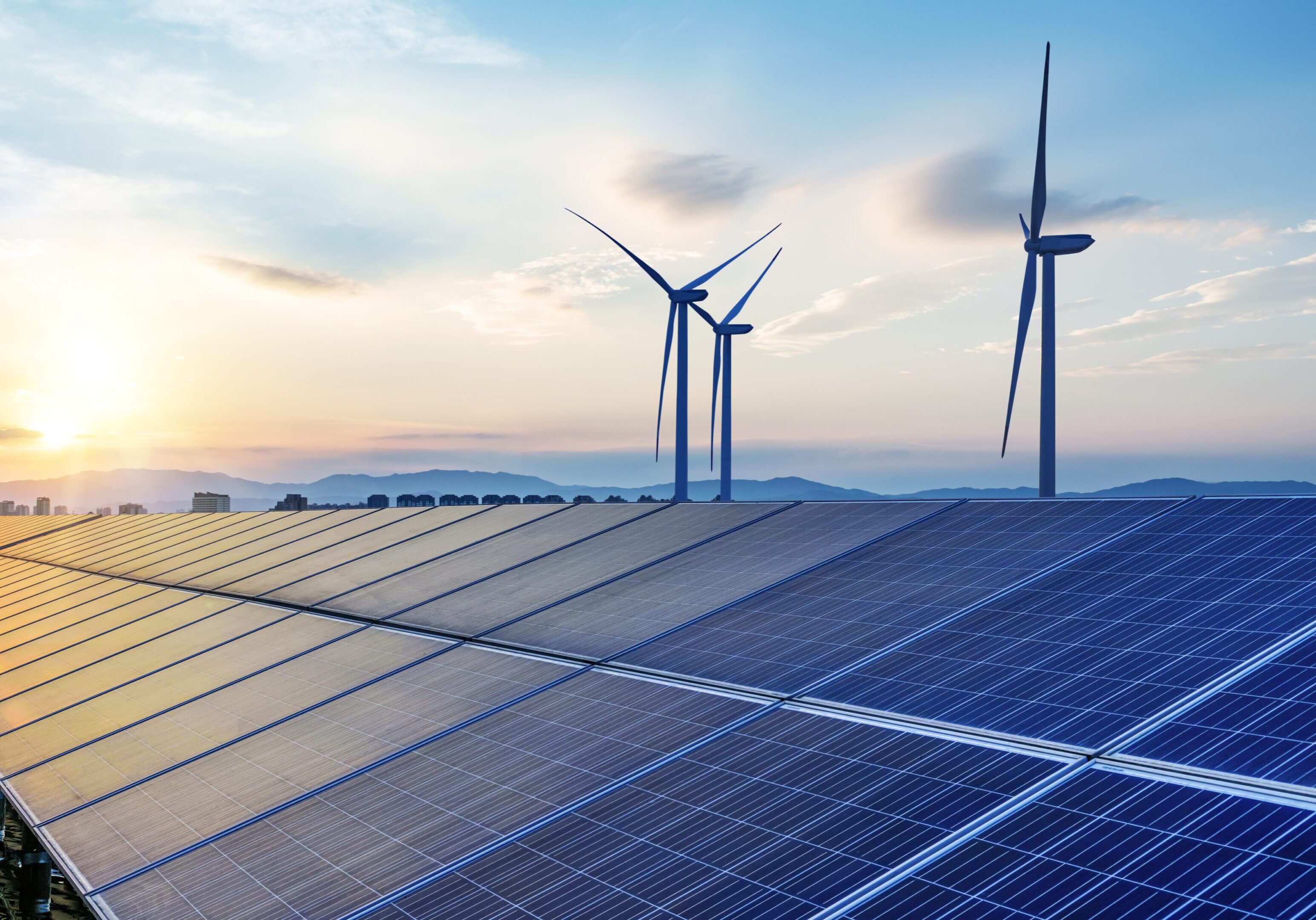 Solar panels and wind turbines at sunset.